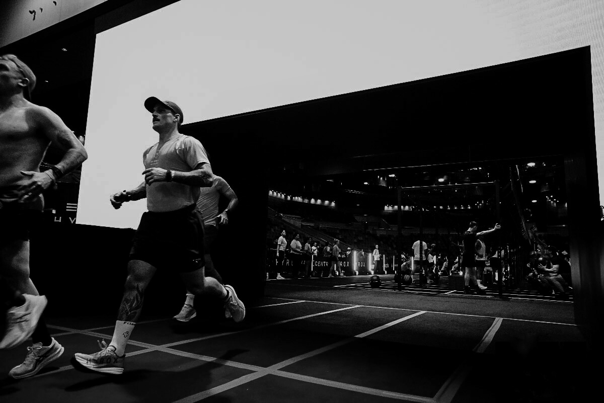 Hybrid athlete running through a dark performance arena